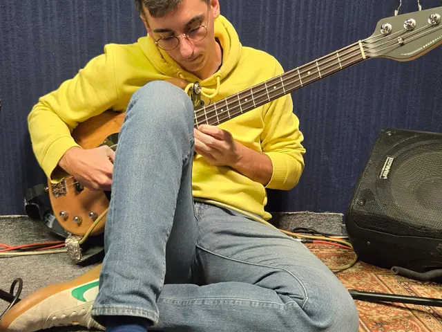 Cours de basse au studio de répétition de Saint-Marcel, assis par terre la basse sur les genoux