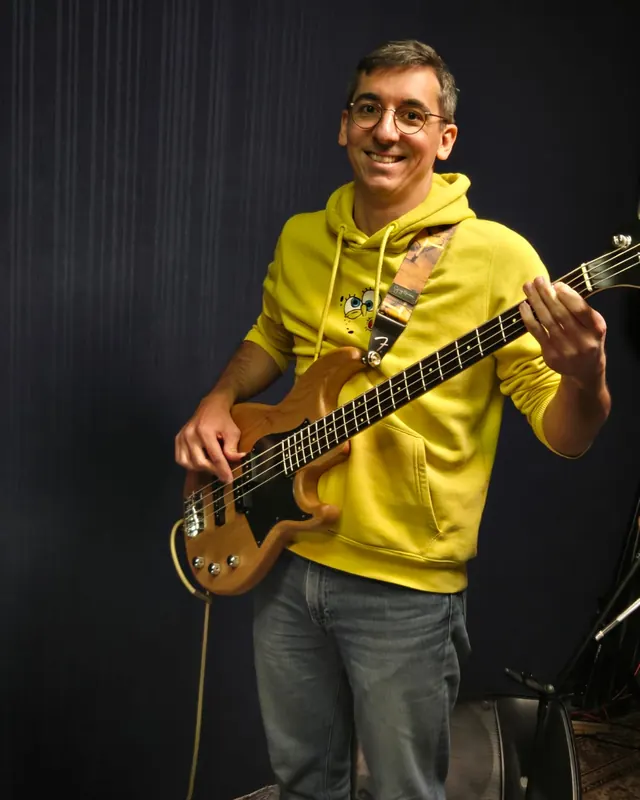 Quentin, professeur de basse à Marseille, sa basse à la main devant le fond sombre du studio